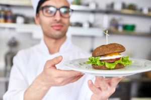 Gyorséttermi dolgozó egy hamburgerrel a kezében